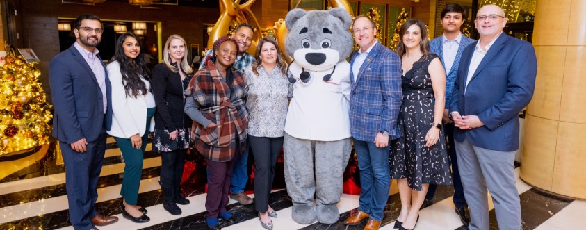 Board members, Dr. Bear and event coordinators standing in the Four Seasons Lobby, which is decorated for Light Up the Season 2022